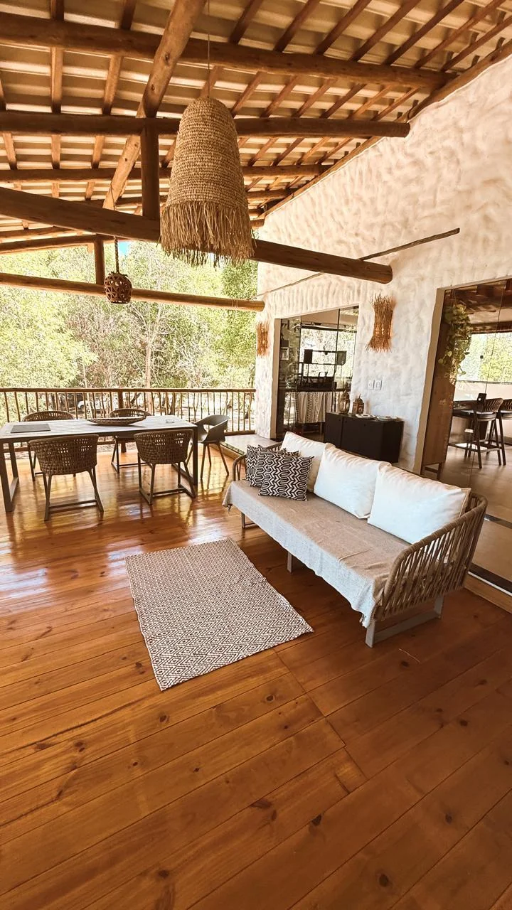 Varanda com sofá e mesa de jantar sob o telhado de madeira
