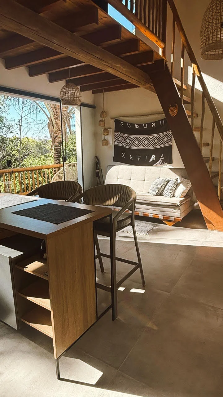 Sala integrada com bancada, sofá e escada para o mezanino