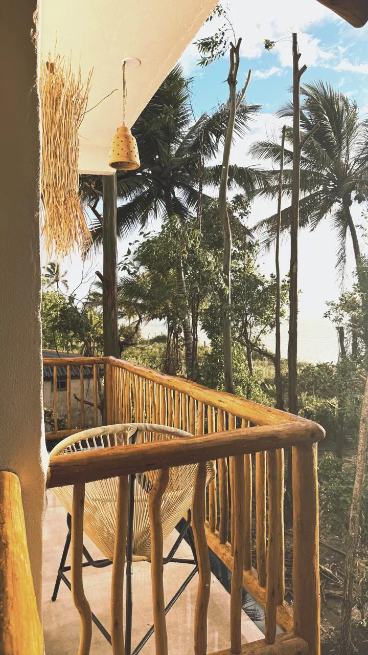 Varanda com cadeira e vista para os coqueiros e o mar